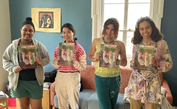 Four students smile while holding the Ankh magazine