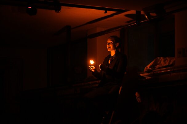 An actor holding a flame in a dark room