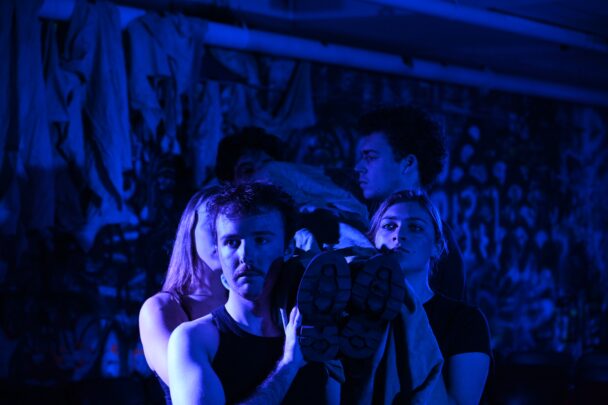 Four actors carry a prop dead body